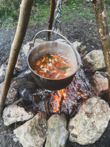 A cooking pot hanging over a fire cooking a stew. 